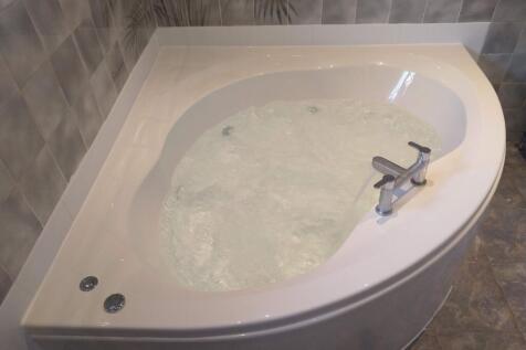 Generous corner whirlpool bath with contemporar...
