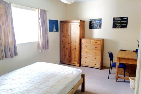 Bright, tidy bedroom with a large window, woode...