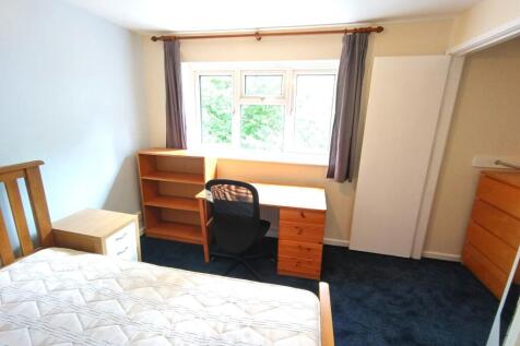 Bright bedroom with a large window, fitted desk...