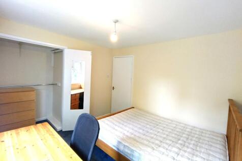 Bright single bedroom with a wooden bed and mat...