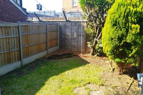 Sunny enclosed rear garden with lawn, mature sh...