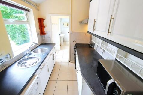 Bright galley kitchen with dark worktops, white...