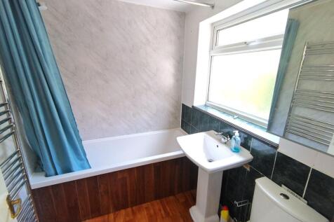 Bright, modern bathroom with a white bathtub, p...