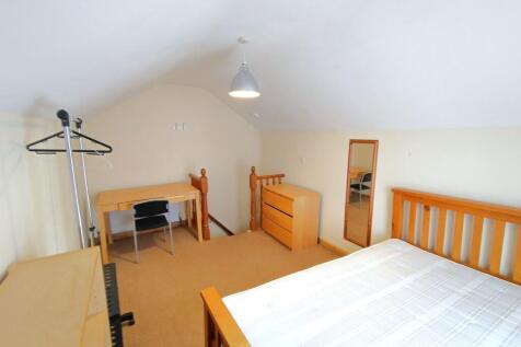 Bright attic double bedroom with wooden bed fra...
