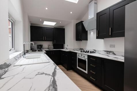 Modern galley-style kitchen with sleek black ca...