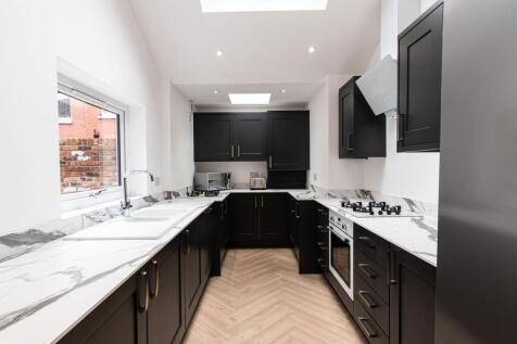Bright, modern galley kitchen with marble-effec...