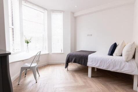Bright, minimalist bedroom with large bay windo...
