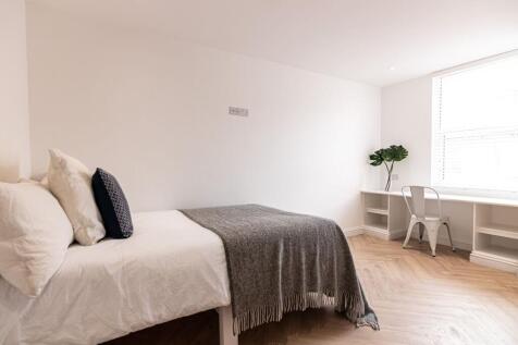 Bright, minimalist bedroom with a neatly made s...