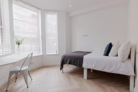 Bright, minimalist bedroom with large bay windo...