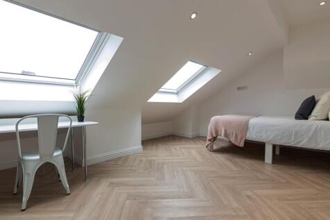 Bright, modern attic bedroom with angled skylig...