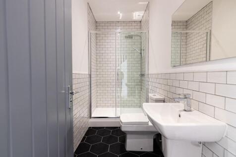 Modern tiled bathroom with a glass-enclosed sho...