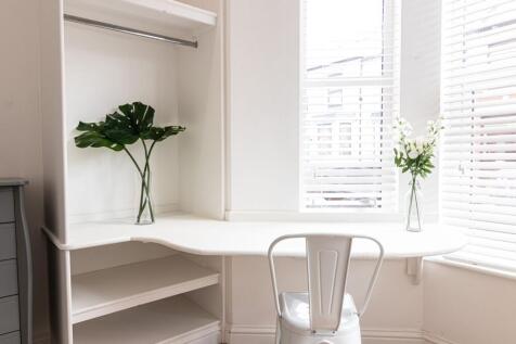 Bright white study nook by a bay window featuri...