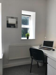 Bright, tidy study corner with a white desk, la...