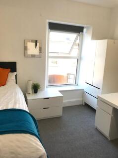 Bright, tidy bedroom with a large window, neutr...