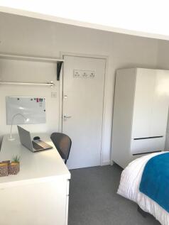 Bright, neatly presented bedroom with a study d...