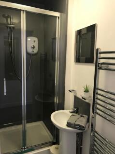 Modern compact bathroom with a glass-enclosed s...