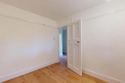 A simple and bright bedroom with white walls an...