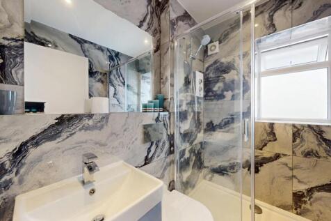 Stylish fully tiled bathroom with striking marb...