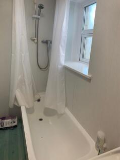Bright, tidy bathroom with a shower over a whit...