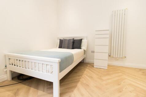 Bright, simply furnished bedroom with a white w...
