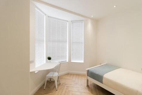 Bright, minimalist bedroom with a large bay win...
