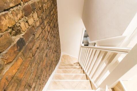 Bright, modern stairway with exposed brick feat...