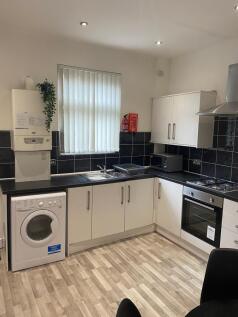 Modern fitted kitchen with white cabinets, blac...