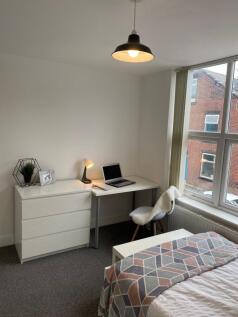 Bright, well-presented bedroom with a desk by a...