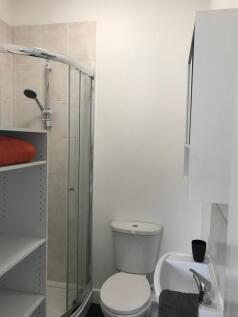 Compact, modern bathroom with a curved glass sh...