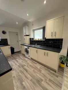 Modern fitted kitchen with pale cabinets, black...