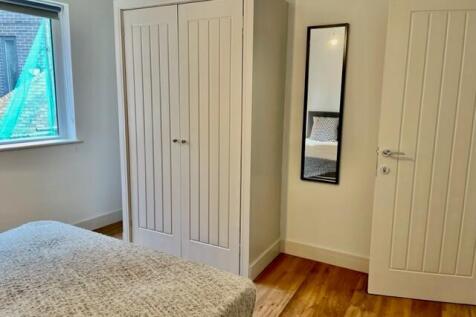 Bright, simply furnished bedroom with a comfy d...