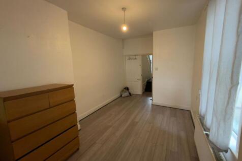 Long, simply furnished bedroom with wood-effect...