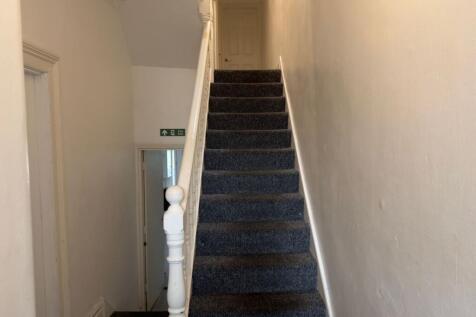 Carpeted staircase with a painted wooden balust...