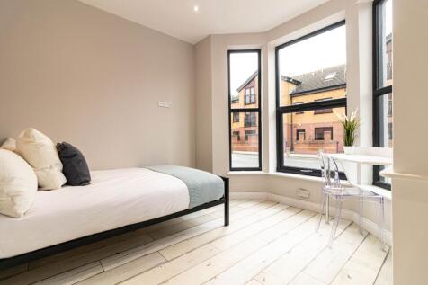 Bright, modern bedroom with large bay windows p...