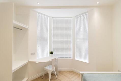 Bright, minimalist bedroom with a bay-window st...