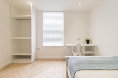 Bright, minimalist bedroom with white walls, pa...
