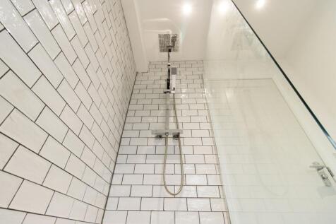 Bright, modern shower with glossy subway tiles,...