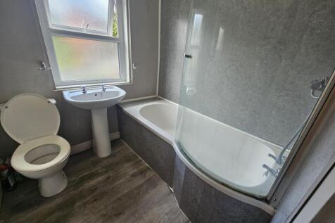 Bright, modern bathroom with a curved shower-ba...