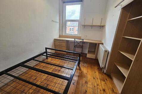 Simple, well-kept bedroom with wooden floors, a...