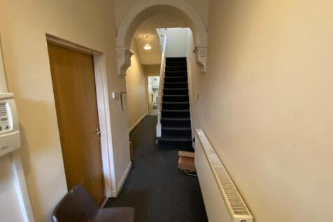 Long entrance hallway with carpeted floor, radi...