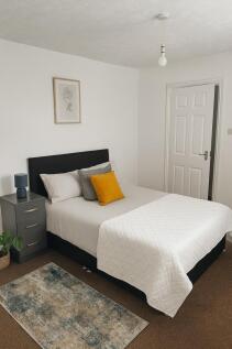 A bright, neatly made bedroom featuring a comfo...