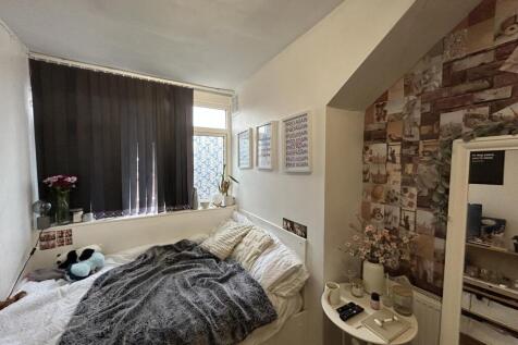 A cozy bedroom featuring a large window dressed...