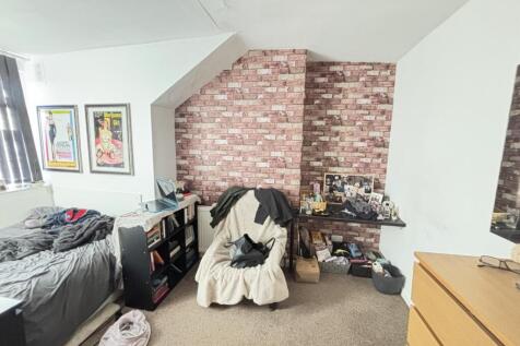 A cozy bedroom featuring a single bed, a study ...