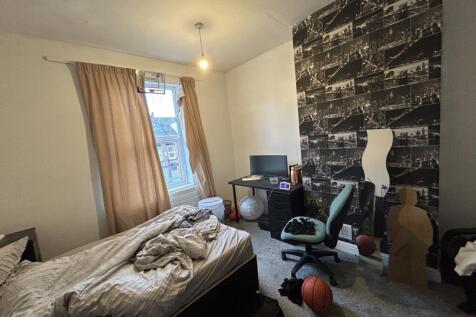 A cozy bedroom featuring a single bed, a study ...