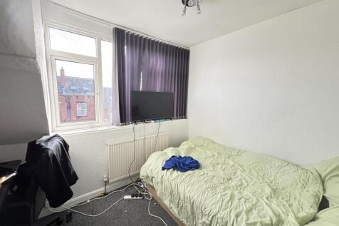 A modest bedroom featuring a single bed, a wind...