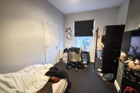 A cozy bedroom with a simple bed, window with a...