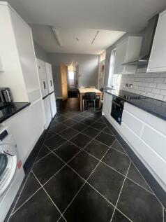 Bright modern galley kitchen with white cabinet...