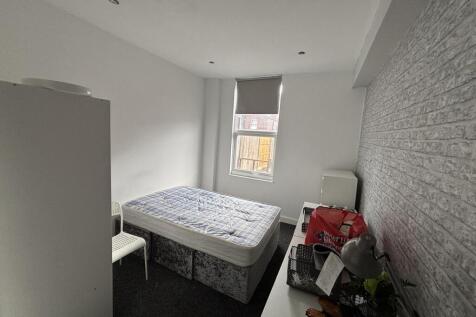 A tidy and well-lit bedroom with a large window...