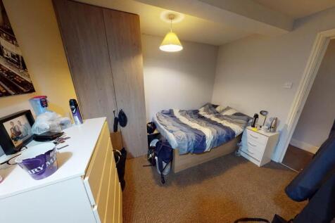 A cozy bedroom featuring a single bed with bedd...