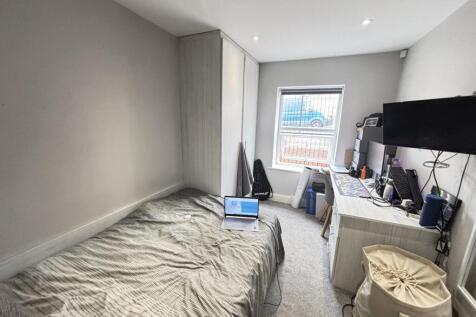 A cozy bedroom featuring a neatly made bed posi...